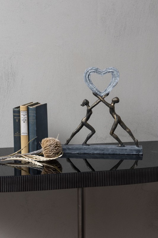 Two figures lifting a heart sculpture