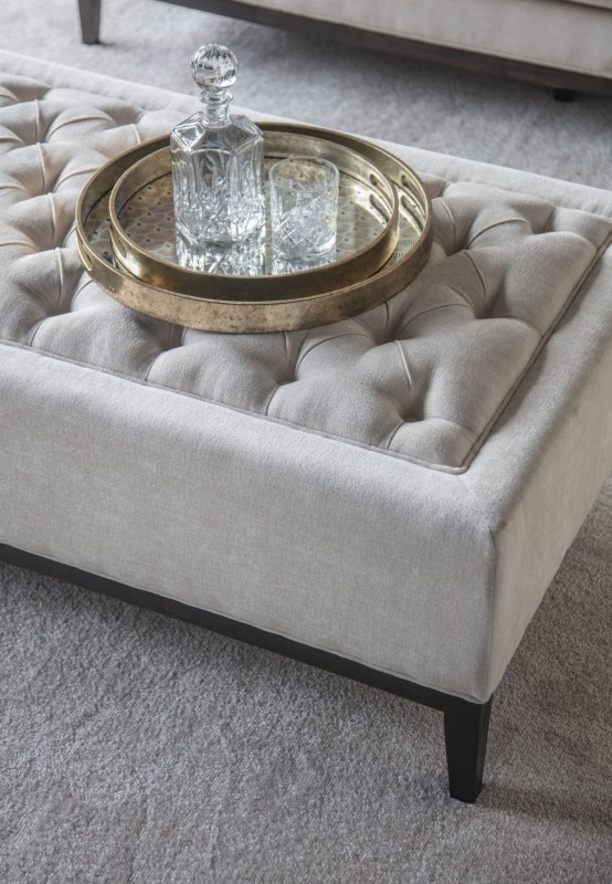 Cream button-tufted ottoman with decorative buttons