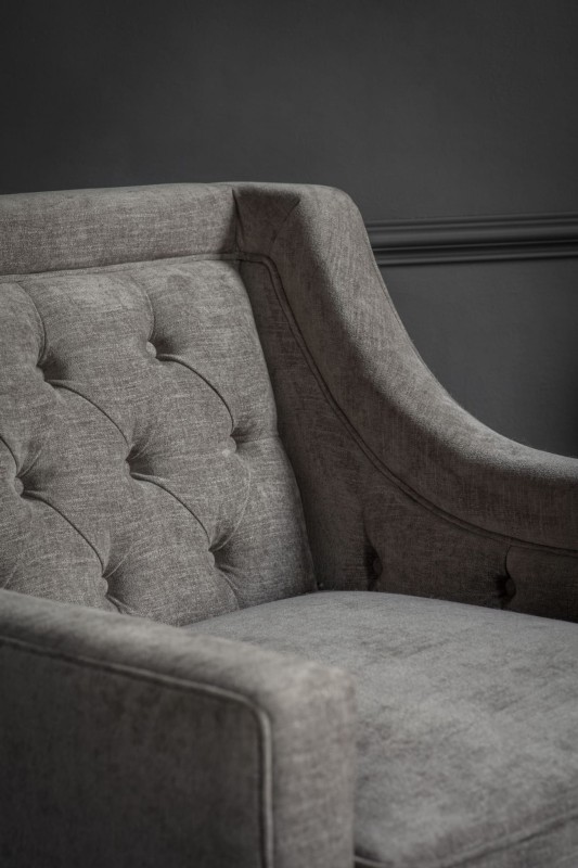 Cheval grey upholstered armchair with button-tufted back and dark wood frame