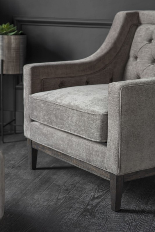 Cheval grey upholstered armchair with button-tufted back and dark wood frame