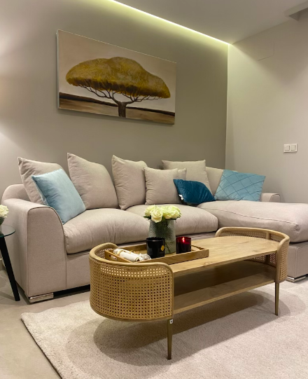 Oval wooden coffee table with rattan cane panels and gold legs