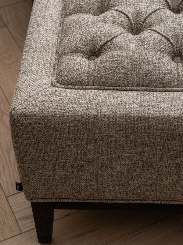 Taupe upholstered footstool on dark wooden legs