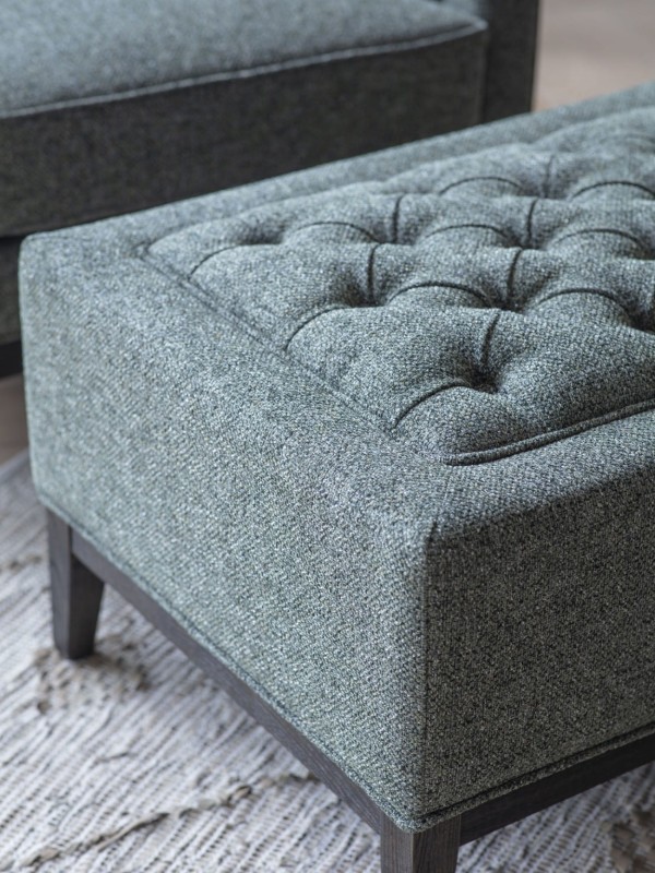 Forest green upholstered footstool on dark wooden legs