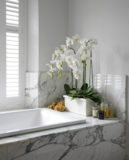 Artificial white orchid with green leaves in a marble planter