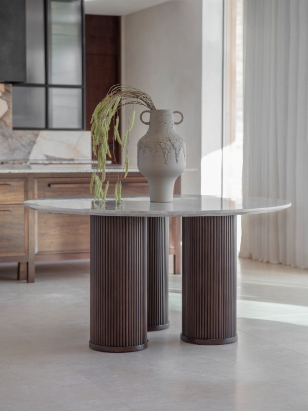 The Bremner round dining table features a marble top and a solid wooden base. With a 150 cm diameter, it is a luxury dining table ideal for elegant dining rooms and modern interiors.