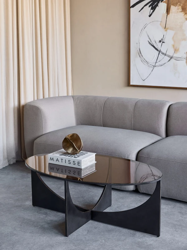 Linton oval glass coffee table with a metal base and refined glass top. Elegant 110 × 65 cm design, perfect for modern living rooms.