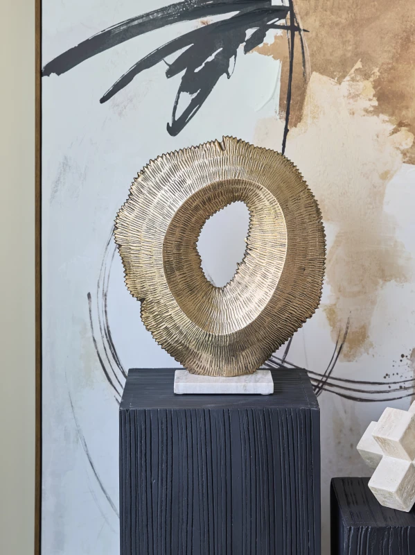 Golden sculpture styled on a black pedestal in a contemporary interior