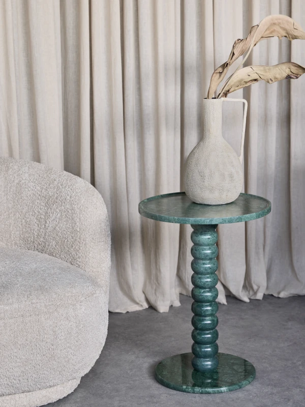 Venice green marble side table beside a cream armchair