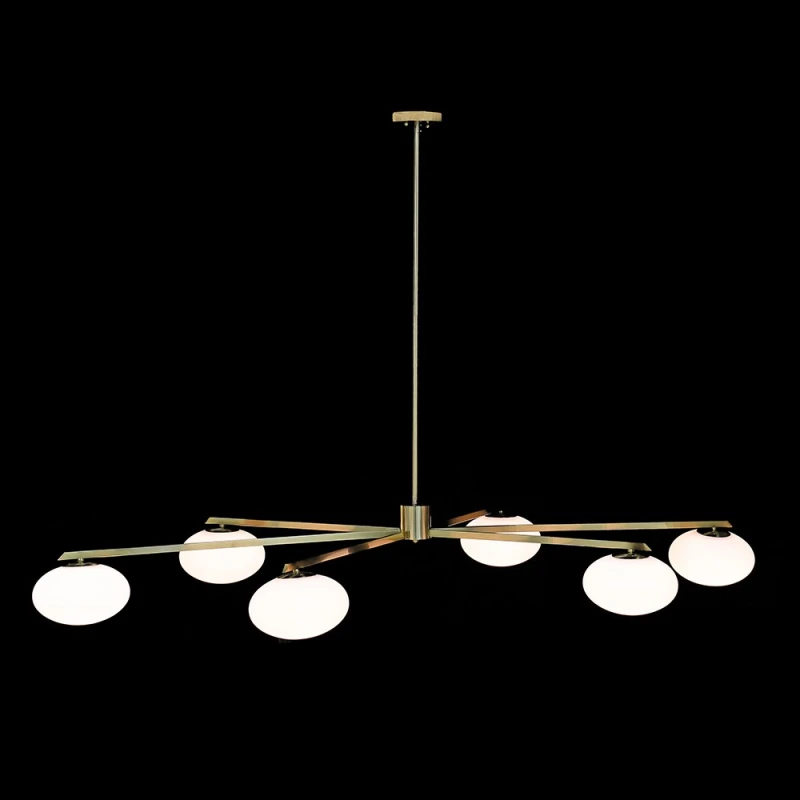 Six-light gold chandelier with white glass globe shades illuminated against a dark background